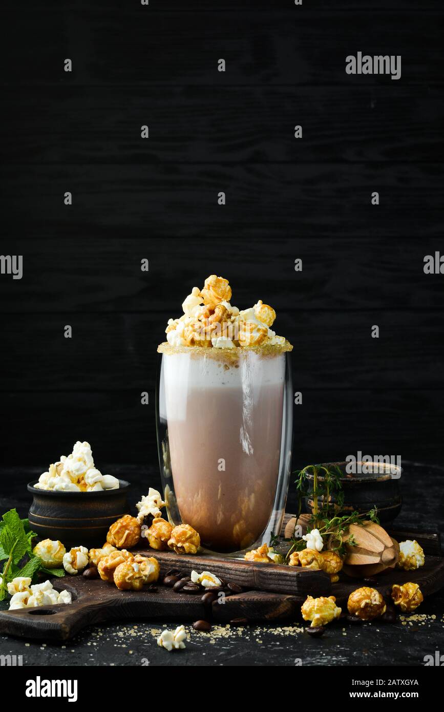 Cacao con latte e popcorn. Nel vetro. Vista dall'alto. Su sfondo nero. Foto Stock