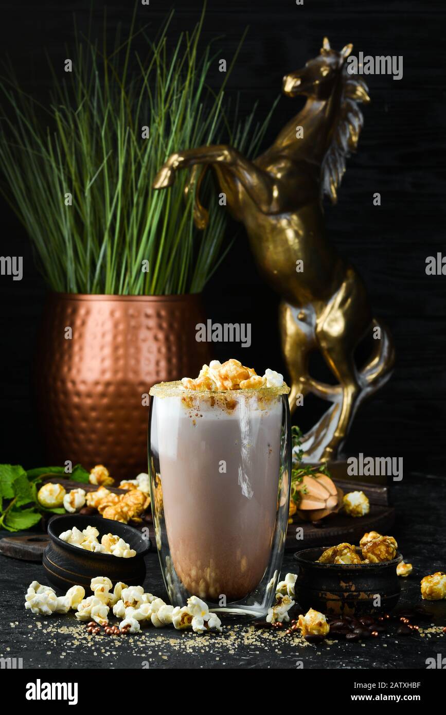 Cacao con latte e popcorn. Nel vetro. Vista dall'alto. Su sfondo nero. Foto Stock
