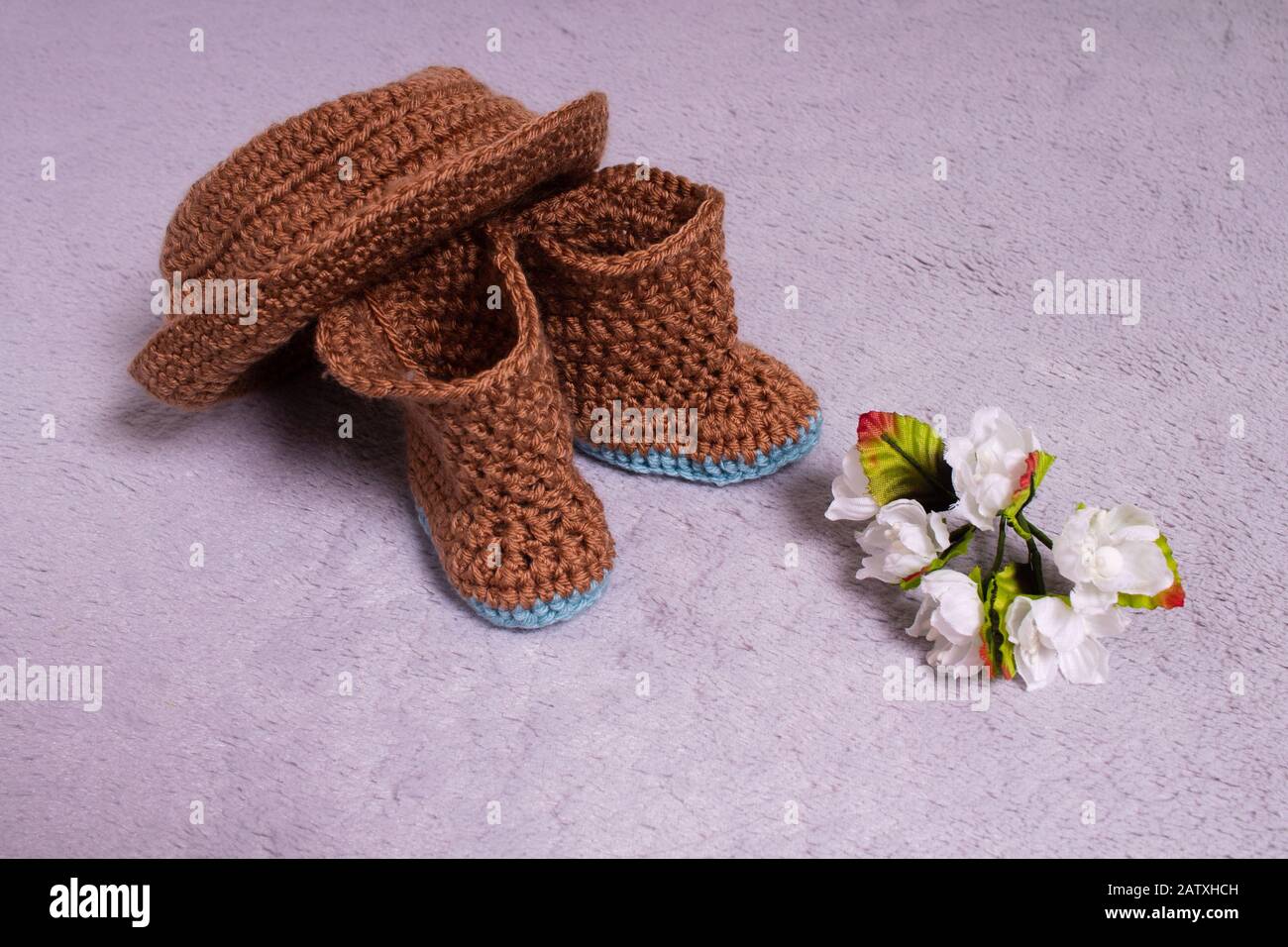 Cappello e stivali a maglia. Scarpe e vestiti in maglia. Stivaletti per bambini. Realizzato a mano. Crochet Foto Stock