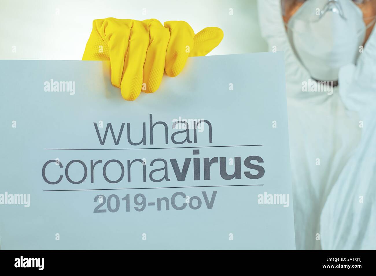 Striscione in carta di avvertimento Wuhan coronavirus tenuto da epidemiologo maschile in indumenti protettivi Foto Stock