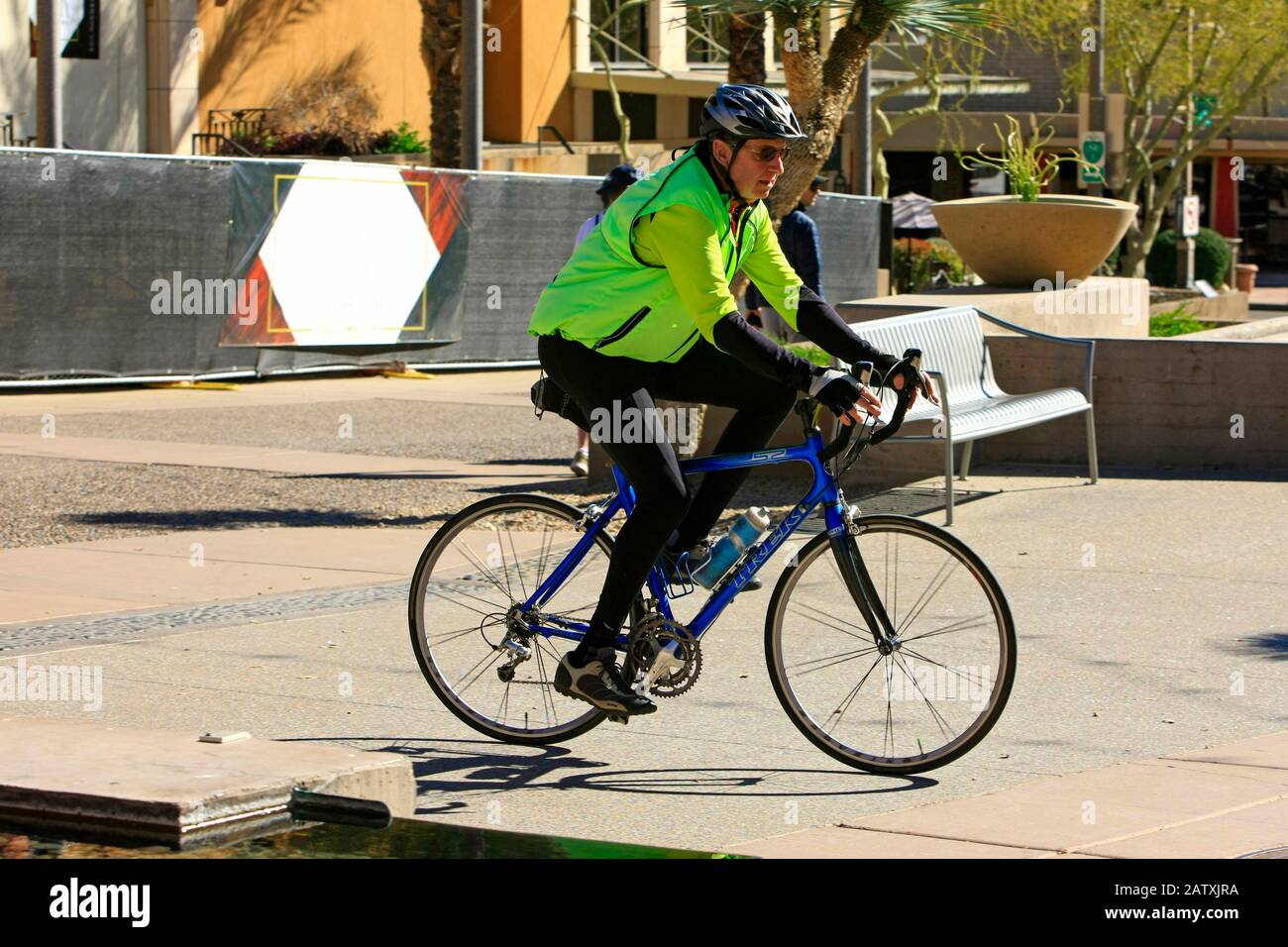 Ciclista maschio indossa una giacca ad alta visibilità mentre guida la sua bici da corsa lungo il percorso ciclabile lungomare di Scottsdale AZ Foto Stock