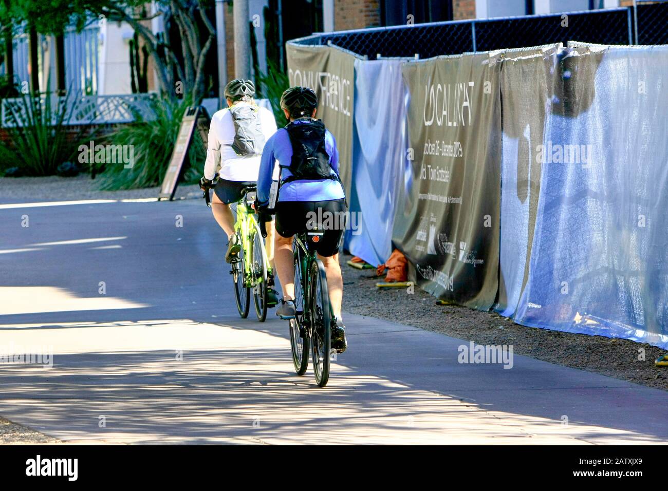 Due persone in bicicletta lungo il quartiere lungomare della città vecchia di Scottsdale AZ Foto Stock