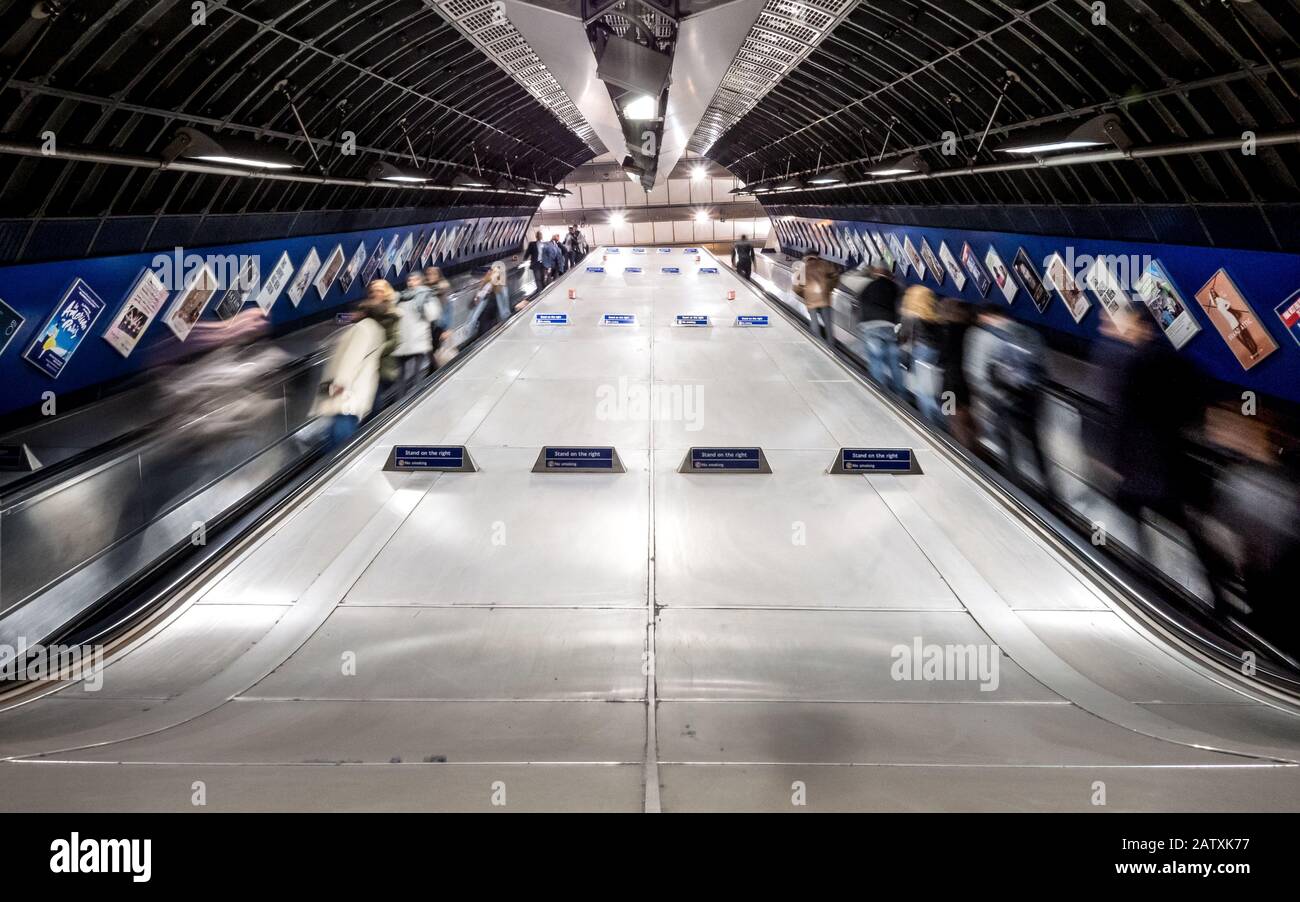 La metropolitana di Londra. Esposizione a lungo la sfocatura del tubo treno viaggiatori e pendolari utilizzando le scale mobili presso la trafficata Stazione della metropolitana di London Bridge. Foto Stock
