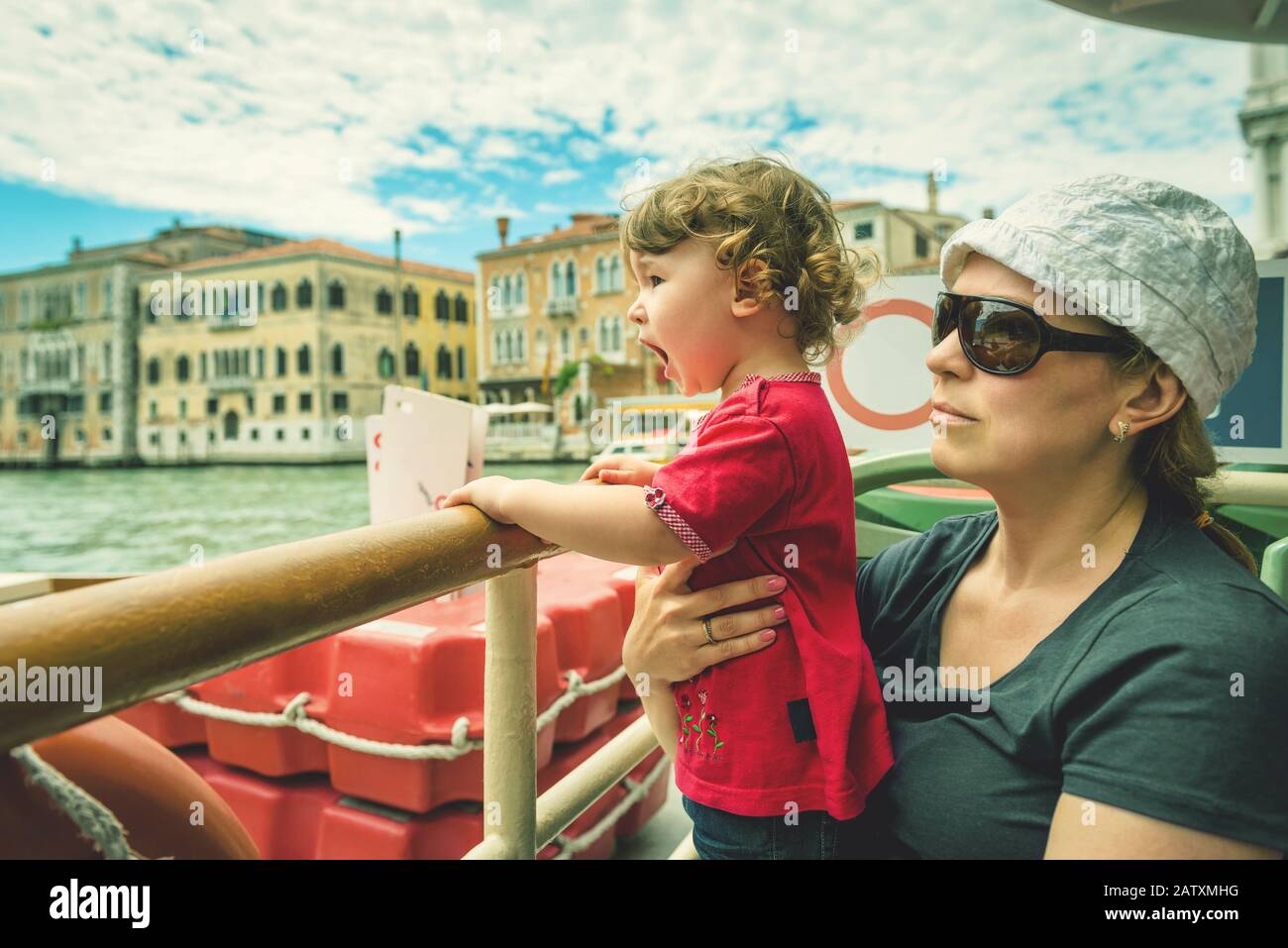 Il bambino carino urla di gioia, essendo con sua madre su una barca turistica sul Canal Grande a Venezia. Il Canal Grande è uno dei principali caffè d'acqua Foto Stock