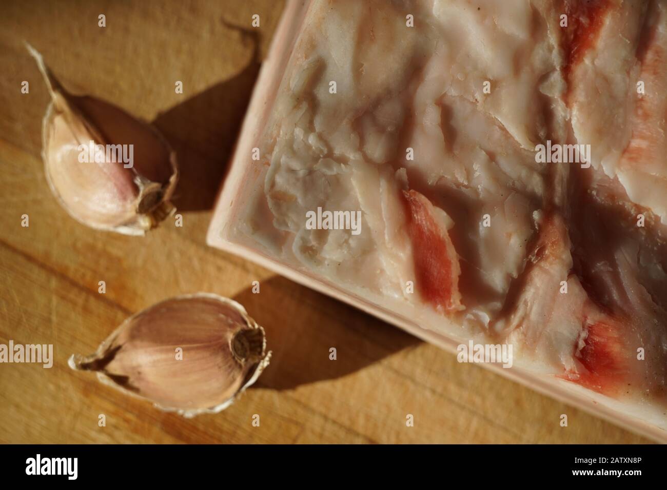 Sul tavolo si trova un pezzo di lardo intero e due spicchi d'aglio Foto Stock