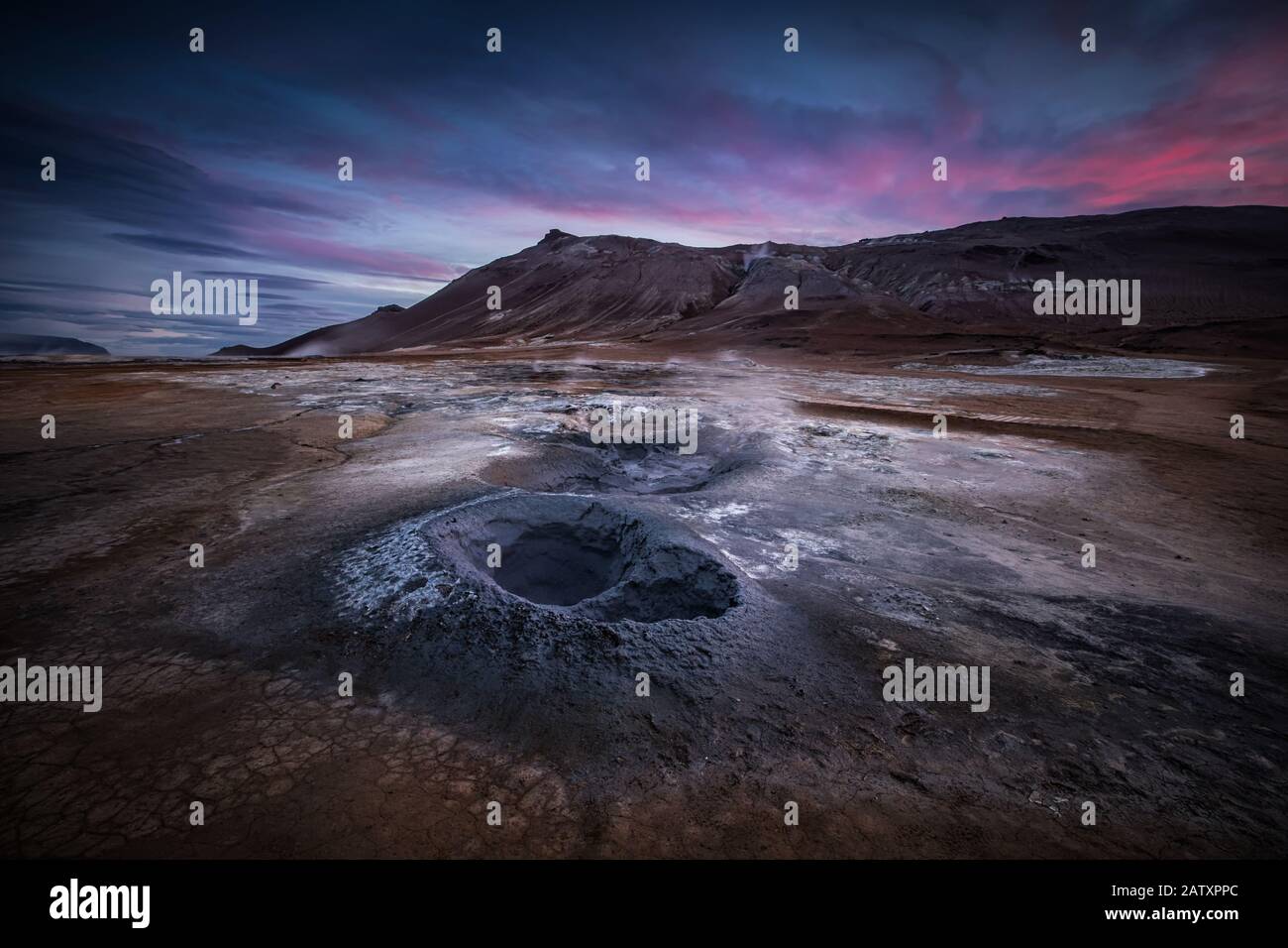 Hverir Geotermal spot notato per le sue gorgoglianti piscine di fango e fumarole fumanti che emettono gas solforico al Tramonto in Islanda Foto Stock