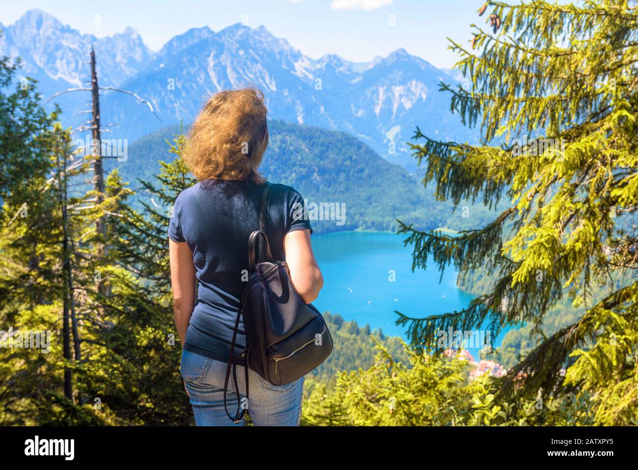 Donna guarda il paesaggio alpino, Baviera, Germania. Vista panoramica sul Lago Alpsee, luogo turistico nella natura. La ragazza adulta viaggia in montagne boscose in su Foto Stock