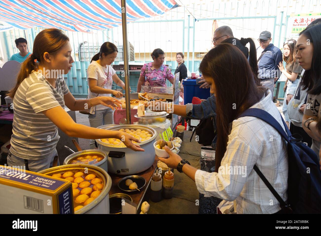 La gente che compra il cibo da una stalla di cibo di strada; mercato di Tai o, villaggio di pescatori di Tai o, isola di Lantau, Hong Kong Asia Foto Stock