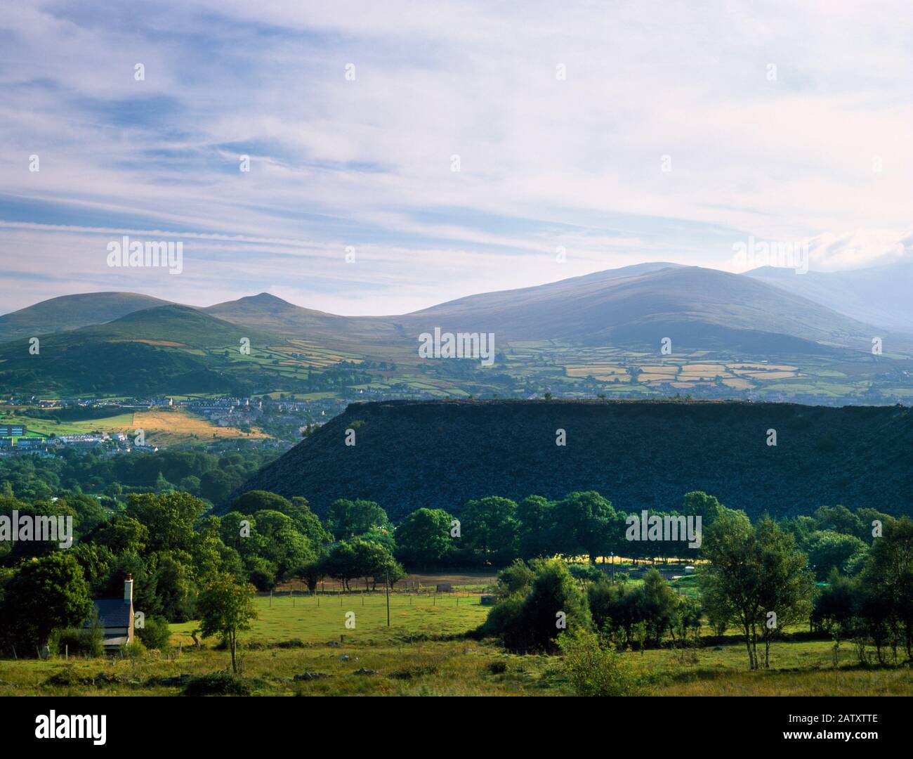 Vedi NE di una punta di spreco disusata nella cava di ardesia di Penrhyn, Galles, Regno Unito, con il villaggio di Bethesda & colline di Gyrn (L) & Gyrn Wigau al retro. Foto Stock