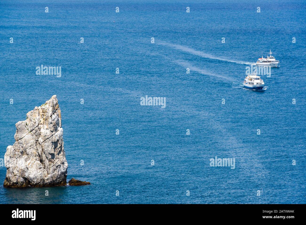 Due barche turistiche navigano oltre la roccia la vela nel Mar Nero vicino a Yalta, Crimea Foto Stock