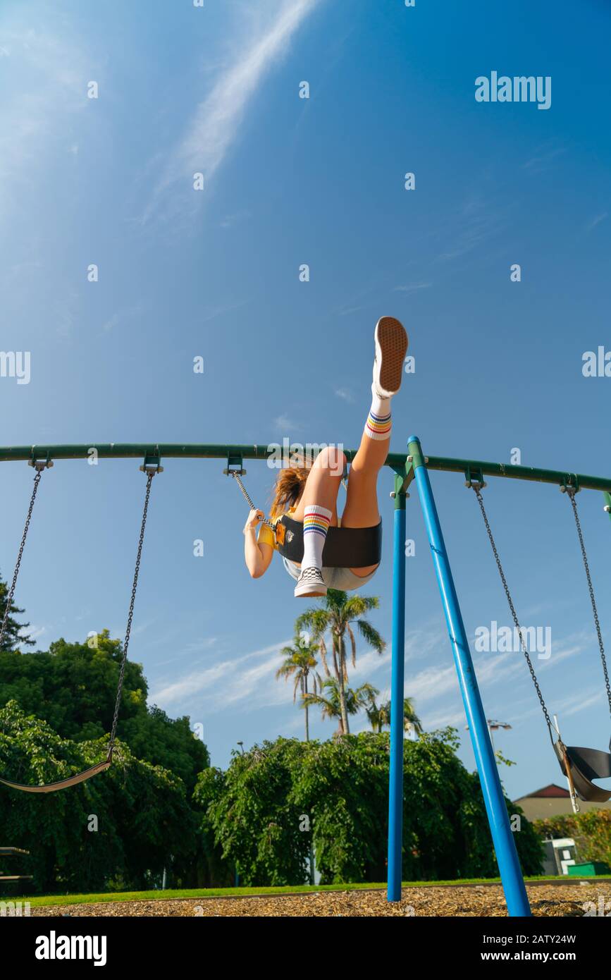 Ragazza adolescente che oscilla in alto nel parco giochi per bambini attrezzature al Tauranga Domain, Nuova Zelanda. Foto Stock