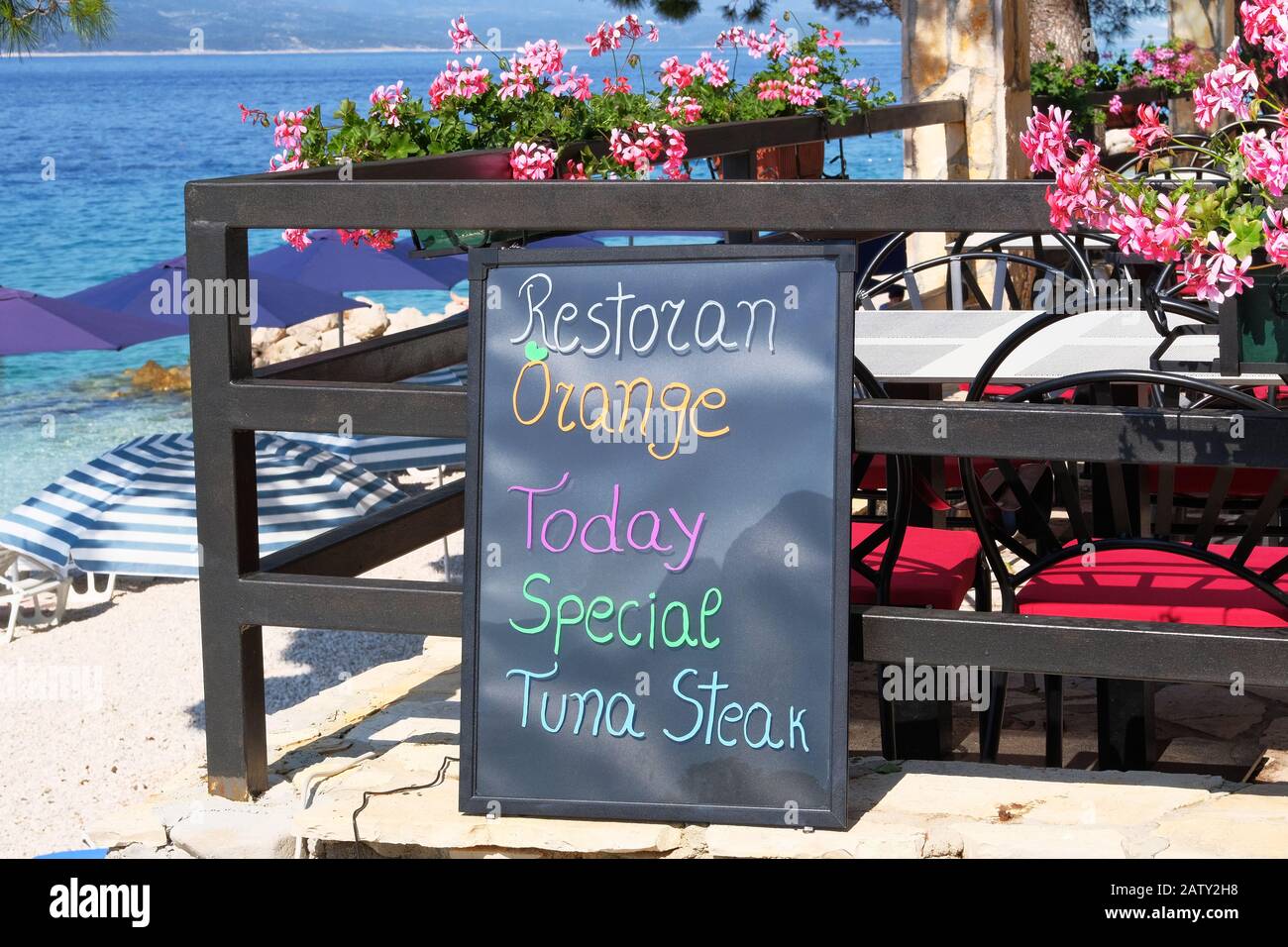 Menù insegna colore nero con iscrizione - ristorante, arancia, oggi, speciale, bistecca di tonno. La lavagna si trova vicino al ristorante sul mare bea Foto Stock