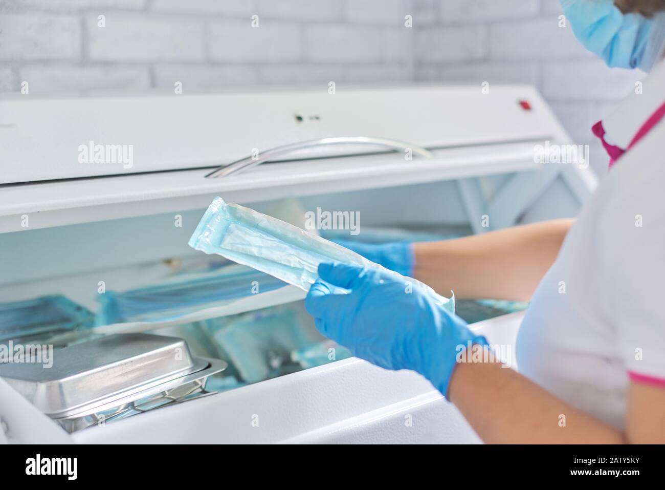 Infermiere femmina che esegue la sterilizzazione di strumenti medici dentali in autoclave. Reparto di sterilizzazione presso la clinica odontoiatrica Foto Stock