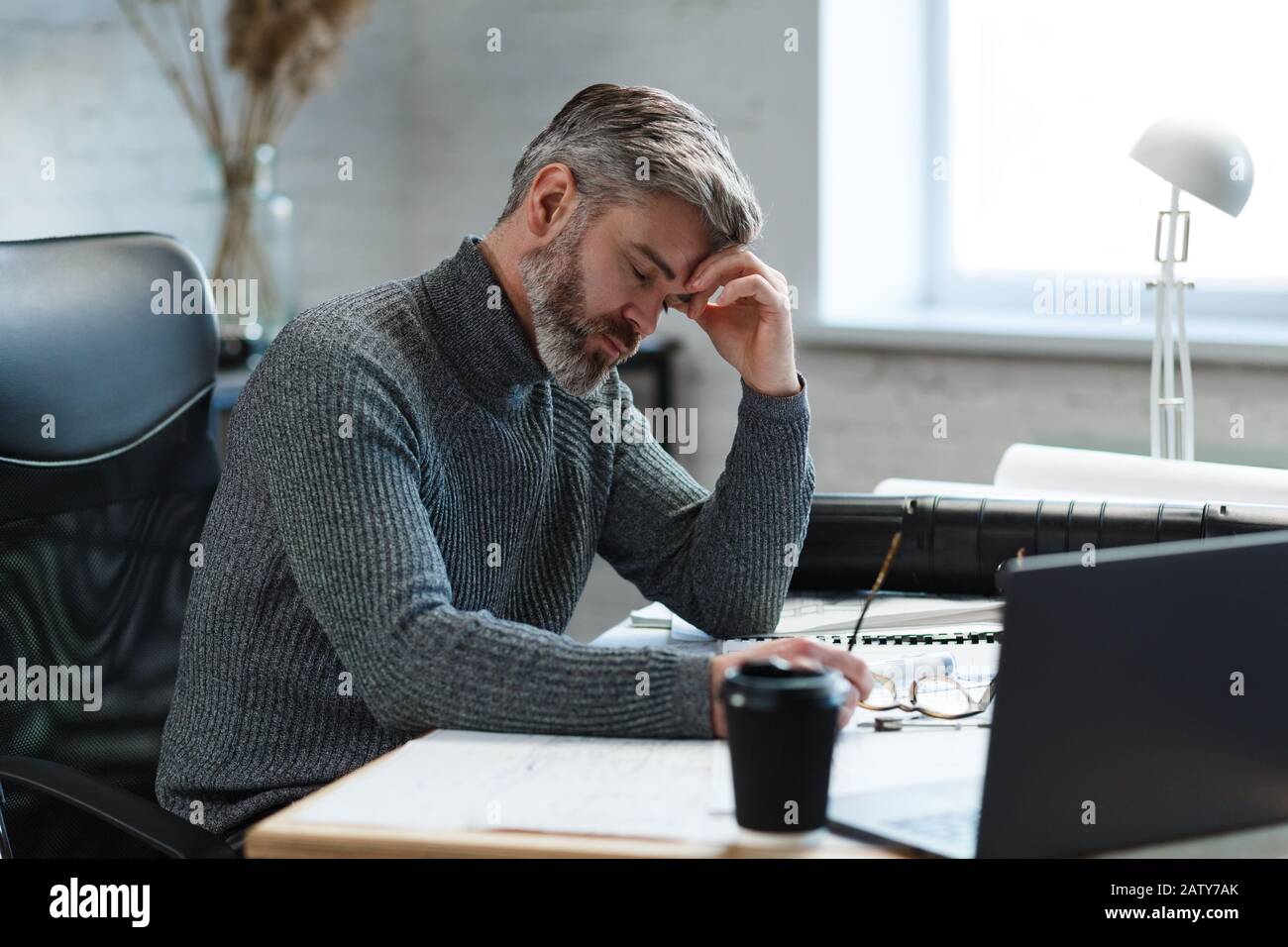 Un architetto stanco che lavora fuori orario. Gli uomini d’affari stressati hanno problemi finanziari e cercano idee per superare la crisi finanziaria. Imprenditore Foto Stock