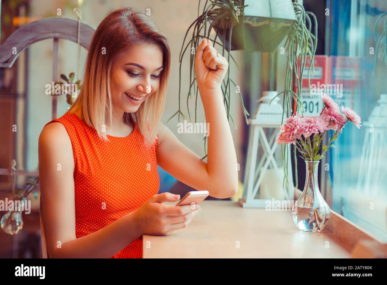 Felice di telefono, vincitore. Donna euforica che guarda il suo cellulare intelligente pompando pugno che celebra guardando felice messaggio foto ha ricevuto sul cellulare a Foto Stock