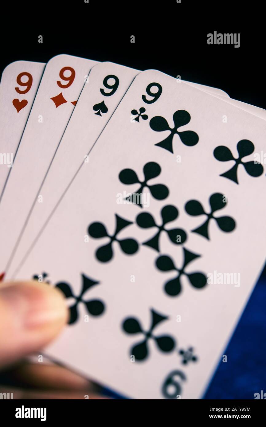 Persona che gioca le carte che tiene una mano di quattro nines Foto Stock