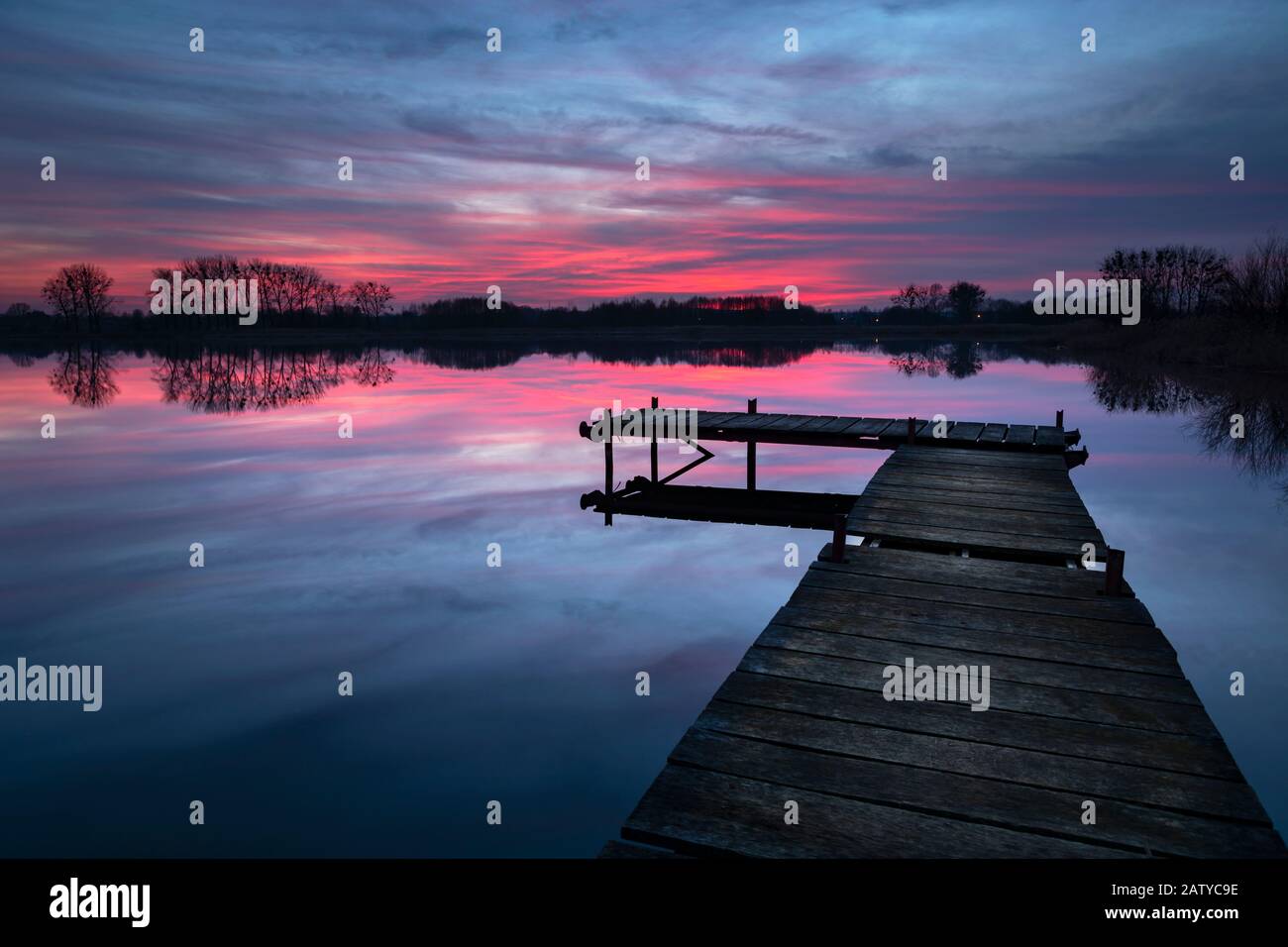 Tramonto con nuvole drammatiche, lago e molo di legno Foto Stock