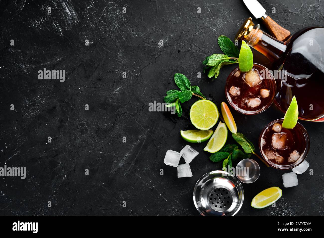Bevande alcoliche Rum, lime e menta su sfondo di pietra nera. Vista dall'alto. Spazio libero per il testo. Foto Stock