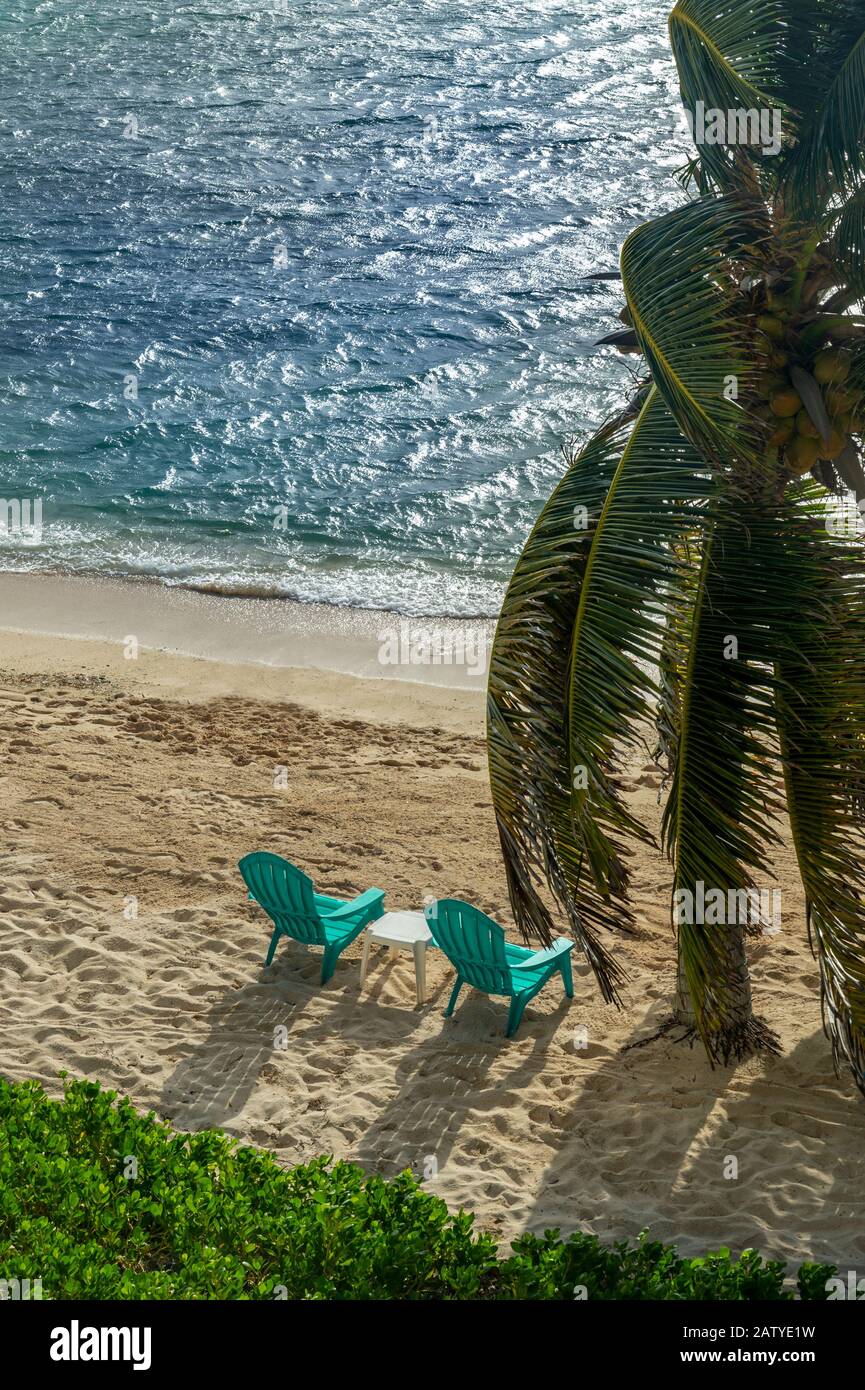Due sedie da spiaggia sulla sabbia con palme e brezza dell'oceano Foto Stock