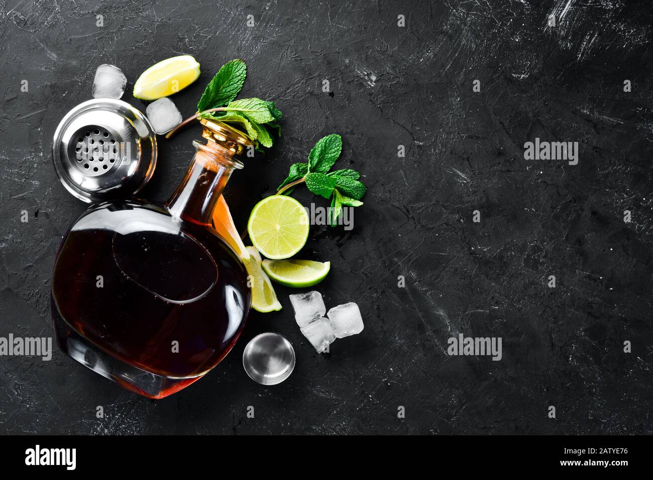Bevande alcoliche Rum, lime e menta su sfondo di pietra nera. Vista dall'alto. Spazio libero per il testo. Foto Stock