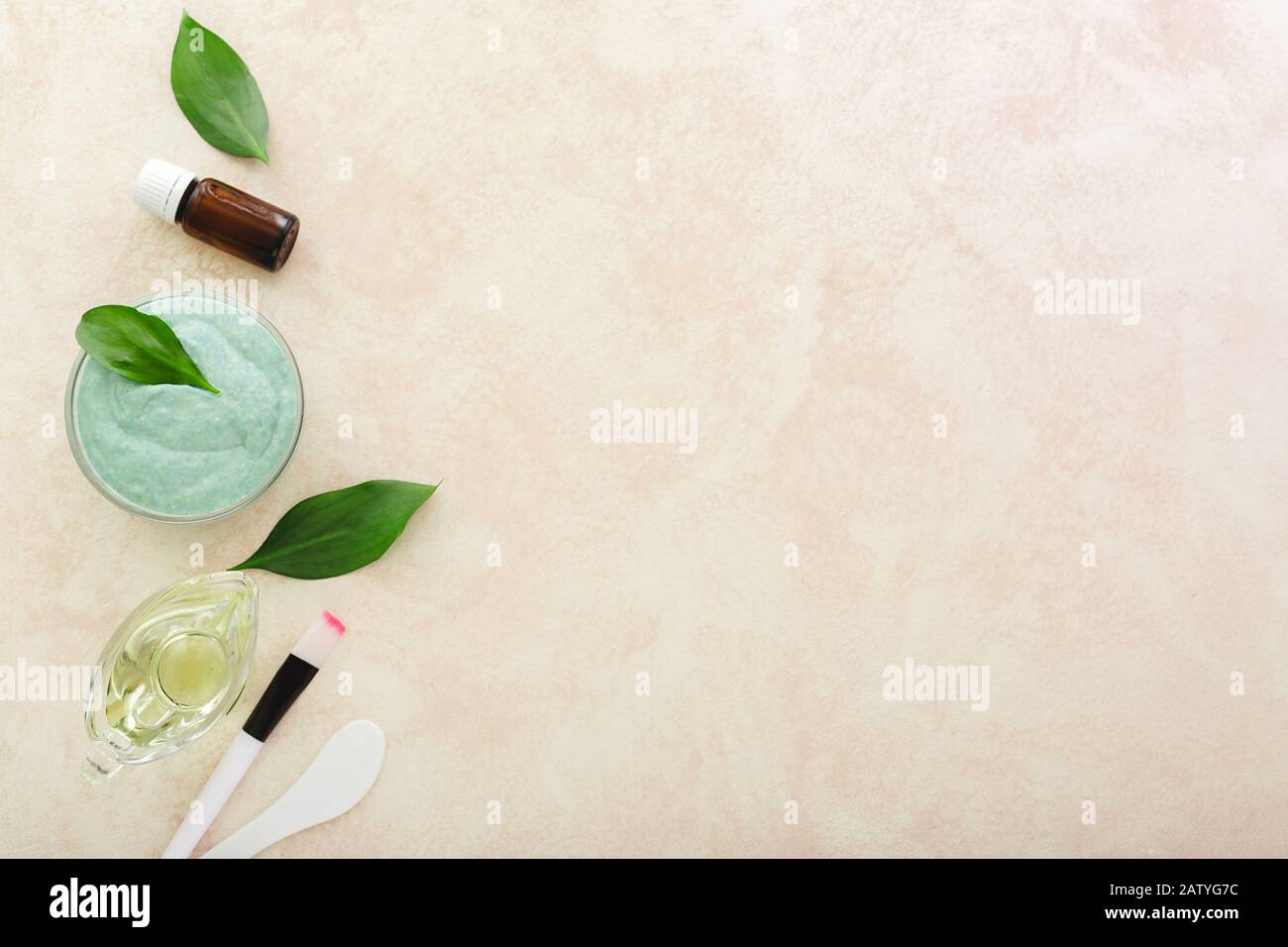 Set di cosmetologia per la cottura, applicazione maschera facciale. Maschera viso avocado, spatola, pennello, olio, olio essenziale su sfondo rosa chiaro con spazio per la copia Foto Stock