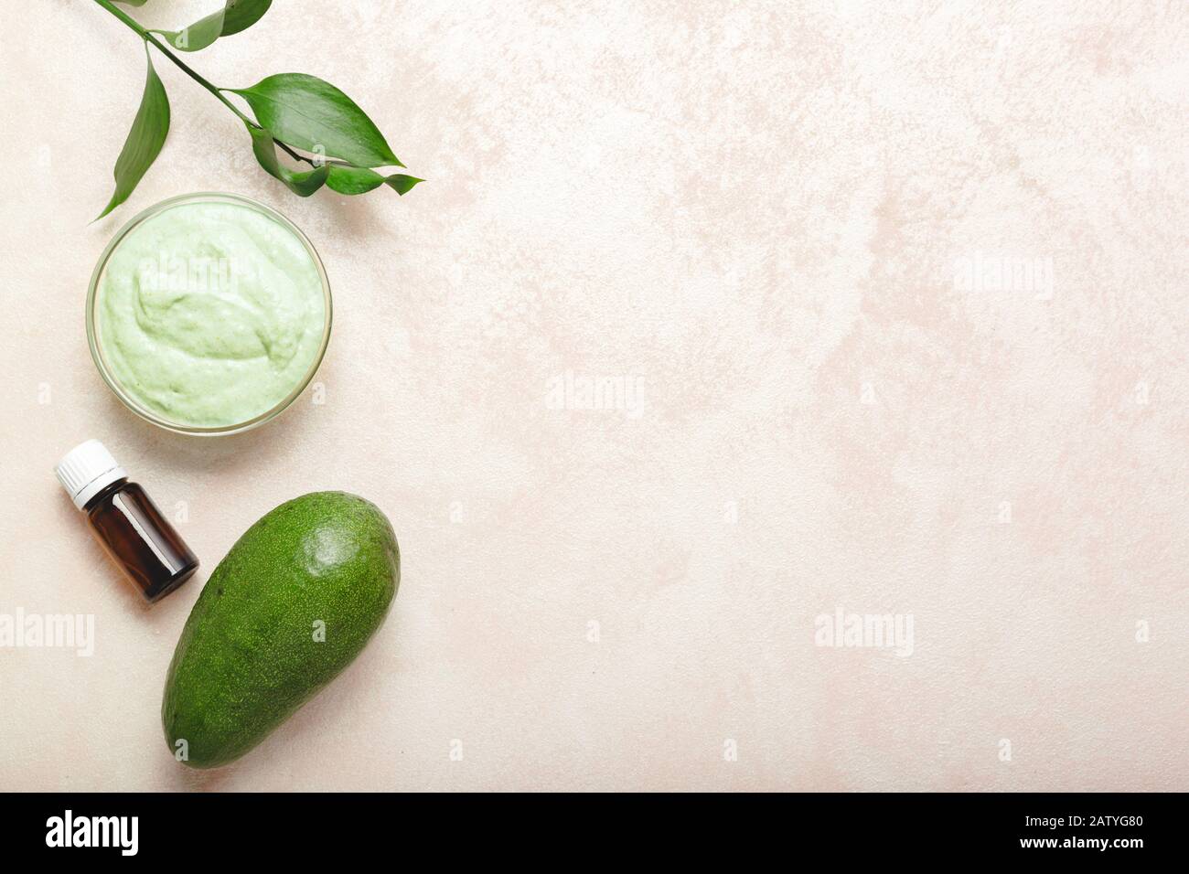 Maschera viso avocado in vaso di vetro con foglie e avocado, olio. Maschera nutriente fatta in casa di avocado purè. Ricetta fai da te per cosmetici Fatti In Casa, pelle Foto Stock