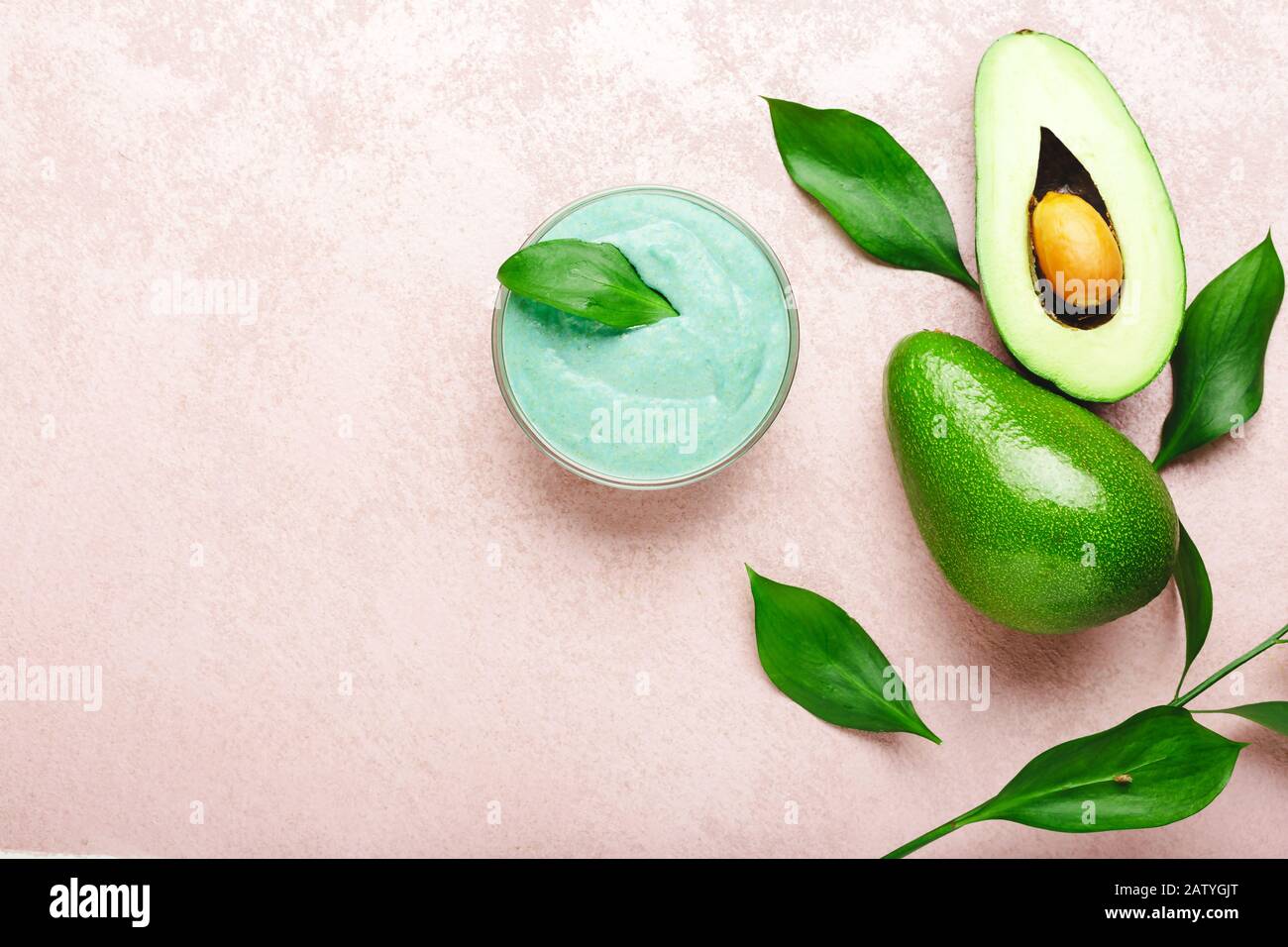 Maschera viso avocado in vaso di vetro con foglie e avocado. Maschera nutriente fatta in casa di avocado purè. Ricetta fai da te per cosmetici Fatti In Casa, cura della pelle Foto Stock