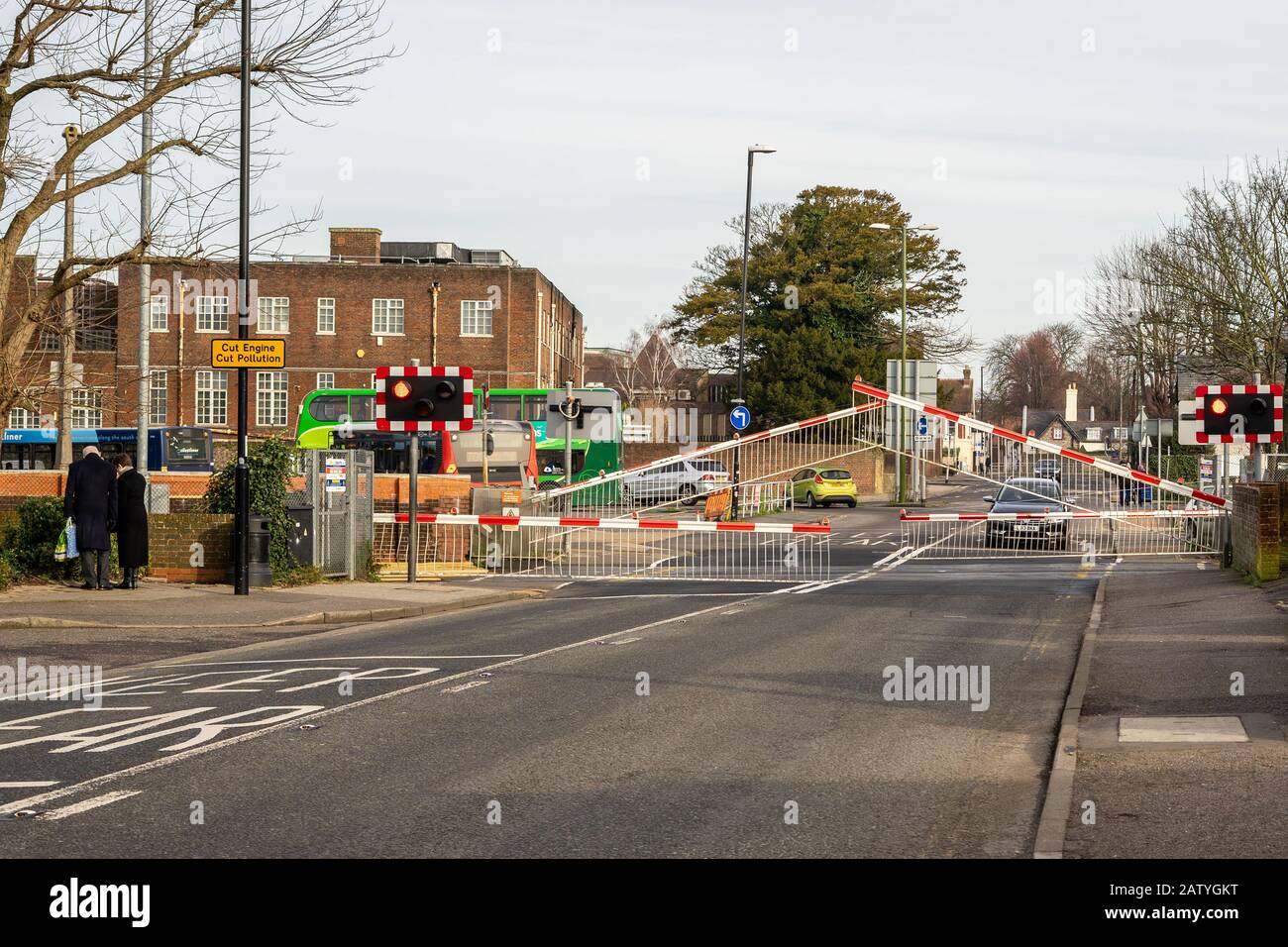 Auto e pedoni in attesa di sollevare le porte ferroviarie ad un incrocio di livello nel centro di chichester Foto Stock