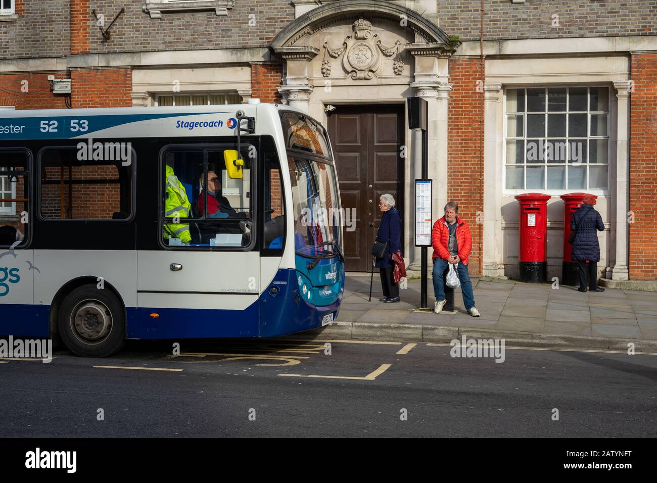 Un autobus di linea a una fermata dell'autobus con pendolari in attesa alla fermata dell'autobus per il loro autobus Foto Stock