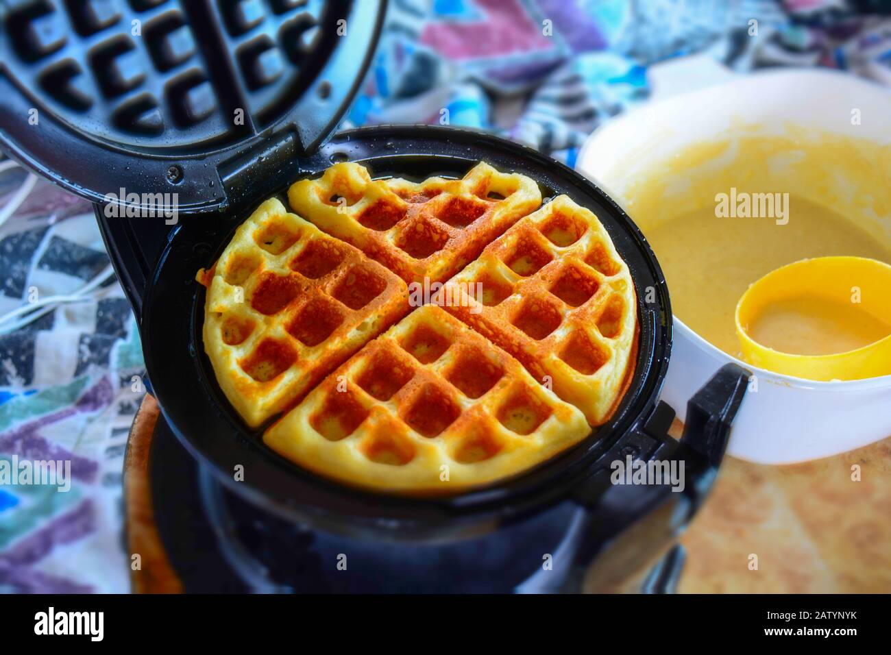 Chiudiere sfocate e colorate di gustosi waffle fatti in casa, caldi e pronti per una colazione familiare la domenica mattina. Ricetta pastella tradizionale, sfondo accogliente Foto Stock