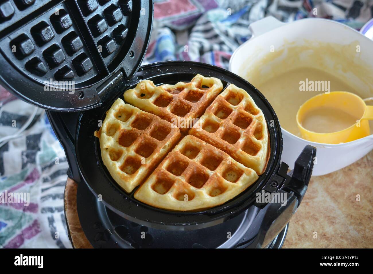 Gustosi waffle fatti in casa, caldi e pronti per una colazione per famiglie la domenica mattina. Ricetta tradizionale pastella fatta da zero, sfondo colorato Foto Stock