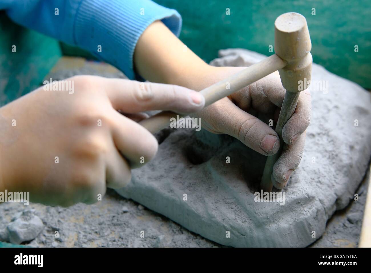 Bambino che gioca fossile, minerale e tesoro scavo gioco. Il bambino utilizza attrezzi, ad esempio un martello. Foto Stock