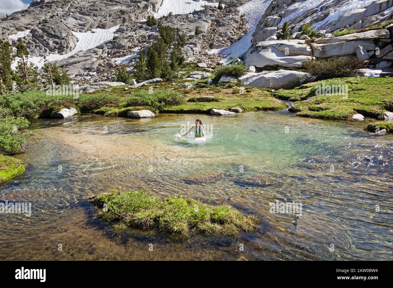 Donna asiatica sconvolta dal tuffo in un freddo ghiacciato ruscello di montagna Foto Stock