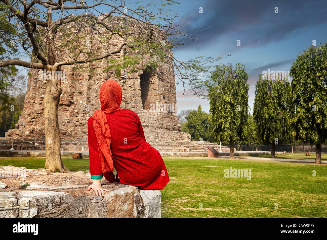 Donna indiana in abito rosso vicino alla torre Qutub Minar a Delhi, India Foto Stock