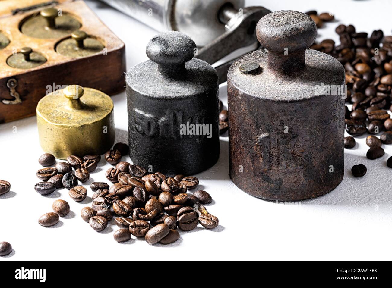 Vecchi pesi rustici in metallo con chicchi di caffè su sfondo bianco. Foto Stock