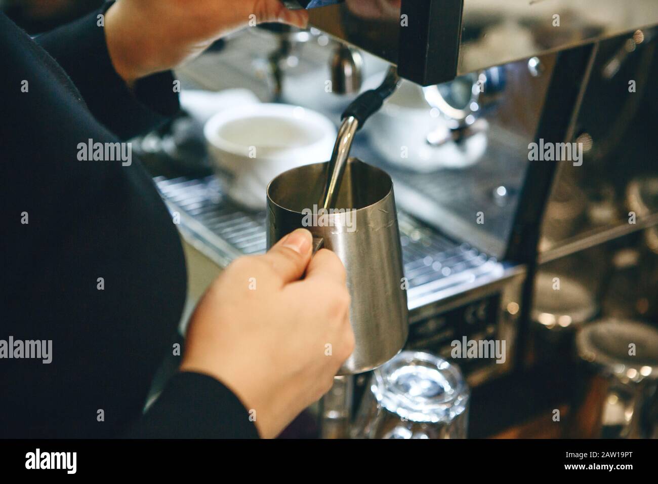 Close-up di un barista preparazione del latte in una macchina da caffè per aggiunta al caffè. Foto Stock