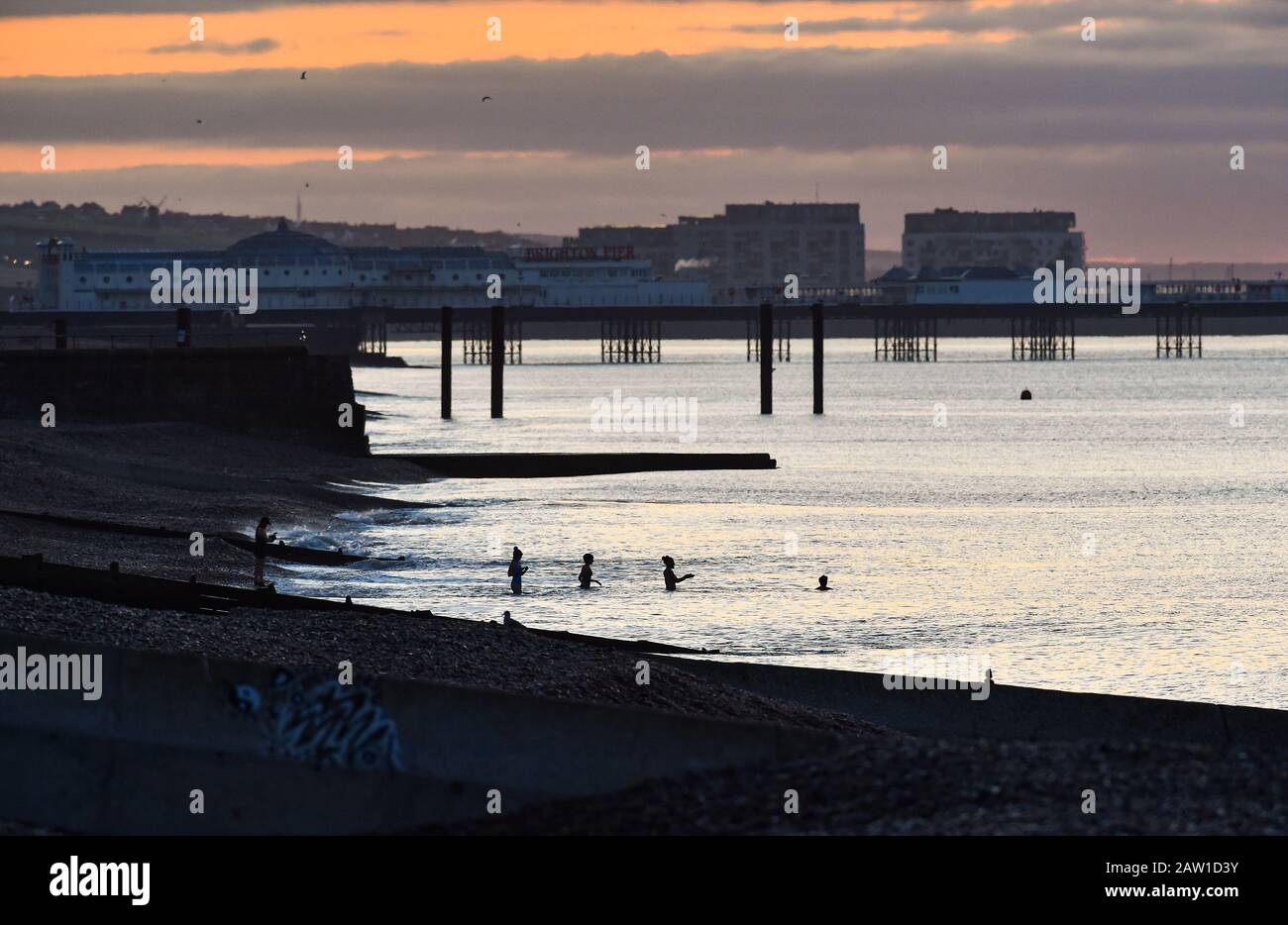Brighton UK 6th Febbraio 2020 - i nuotatori del mattino presto si avventurano nel mare per un tuffo freddo mentre il sole sorge sul lungomare di Brighton. Più bel tempo stabilito è previsto per la prossima coppia di giorni in Gran Bretagna prima che il tempo tempestoso è impostato per arrivare durante il fine settimana . Credito: Simon Dack / Alamy Live News Foto Stock