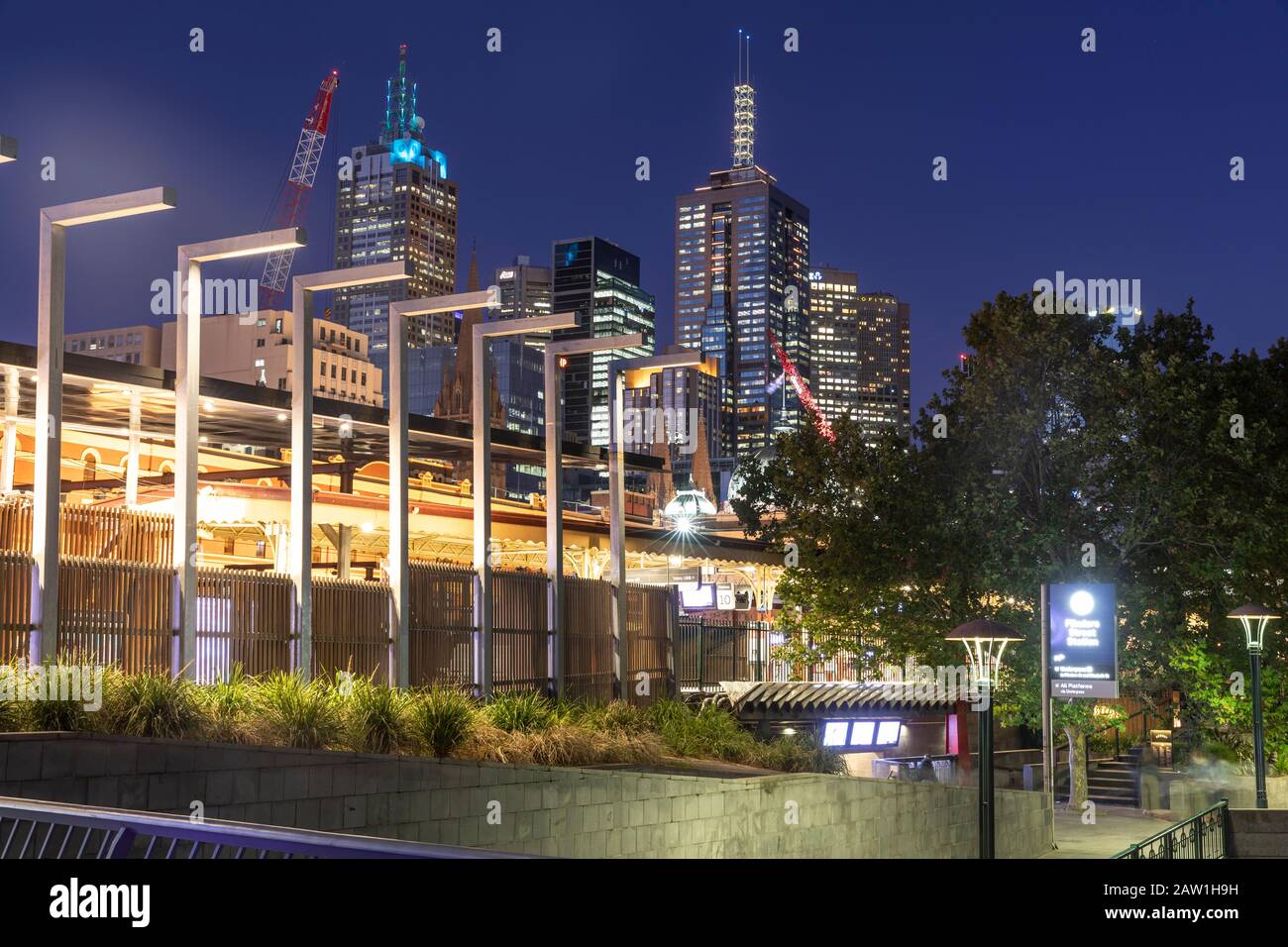 Stazione ferroviaria di Flinders Street di notte nel centro di Melbourne con torri di uffici illuminate, Victoria, Australia Foto Stock