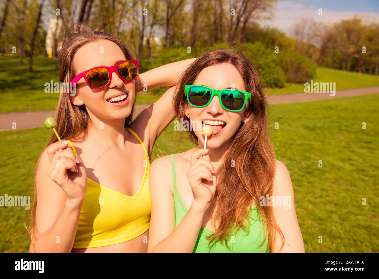 Allegre girlfriends in occhiali che lecca chupa chups Foto Stock