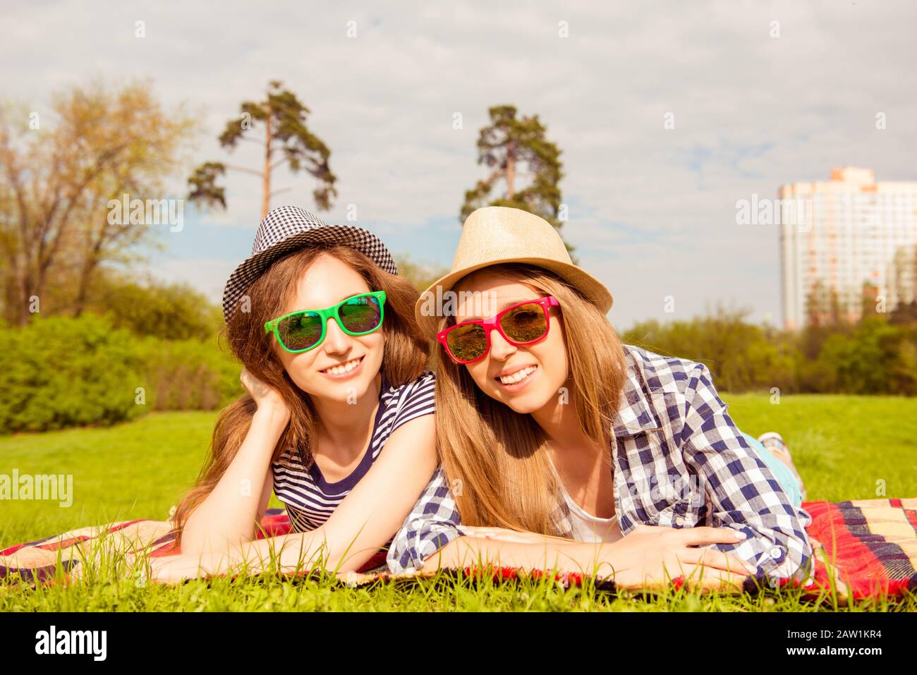 Ragazze graziose in cappelli e bicchieri che hanno picnic nel parco Foto Stock
