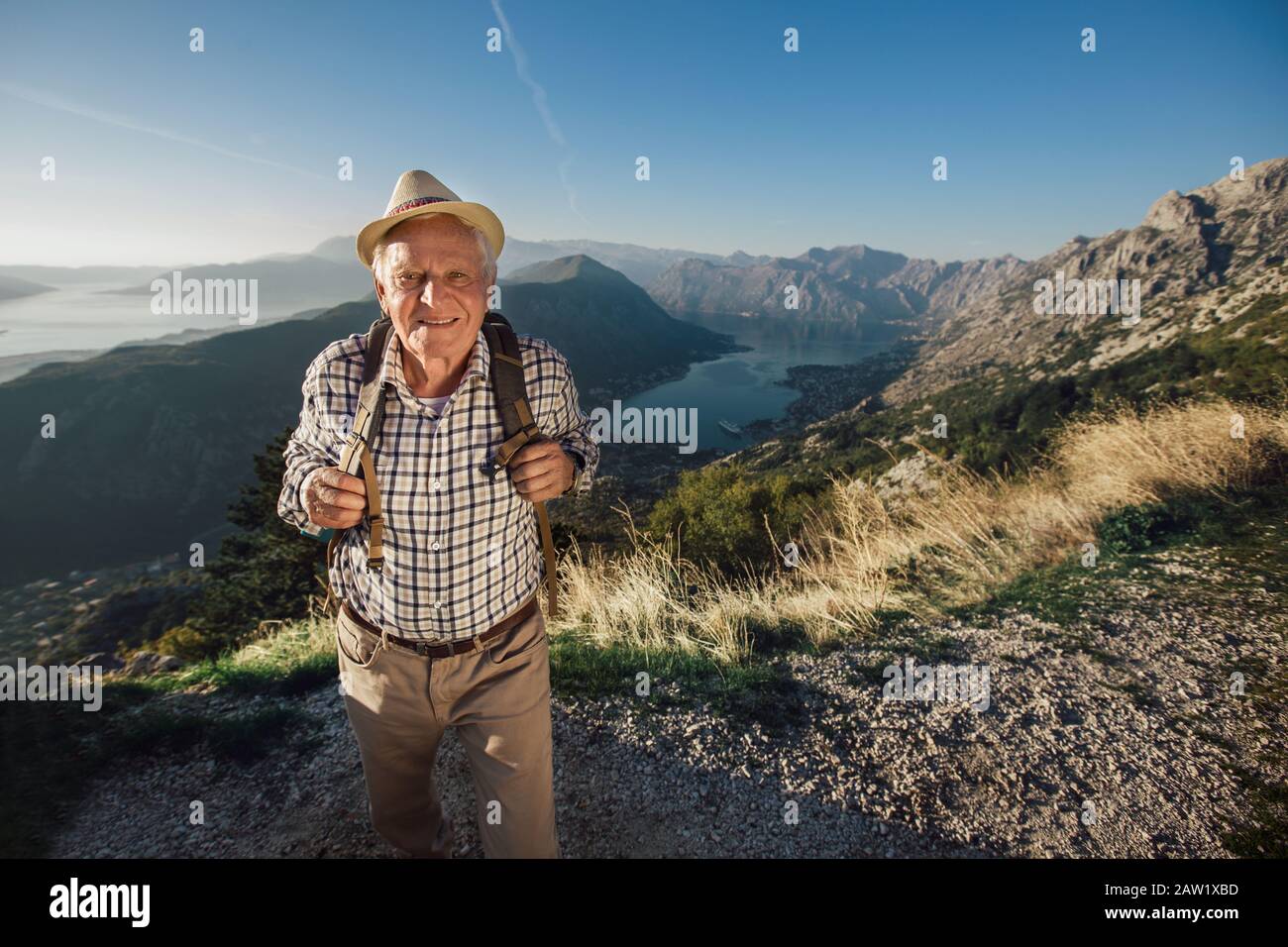 L'uomo vecchio felice raggiunge appena la cima della collina.Bell'uomo anziano che fa trekking, esplorando. Foto Stock