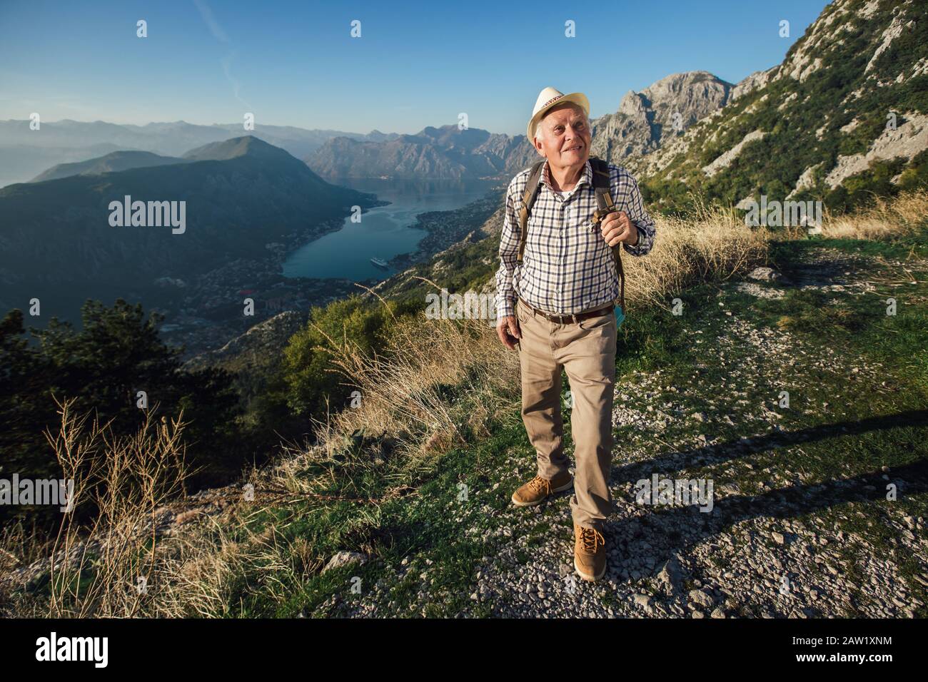 L'uomo vecchio felice raggiunge appena la cima della collina.Bell'uomo anziano che fa trekking, esplorando. Foto Stock