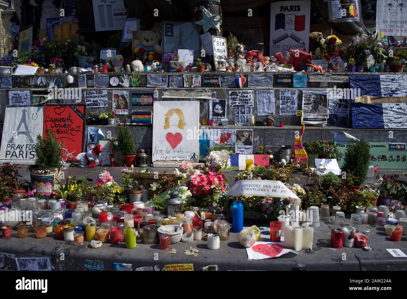 Messaggi scritti a mano, candele e fiori su gradini della statua di Marianne, dopo gli attacchi terroristici di Parigi, Place de la République, Parigi, Francia - aprile 2016 Foto Stock