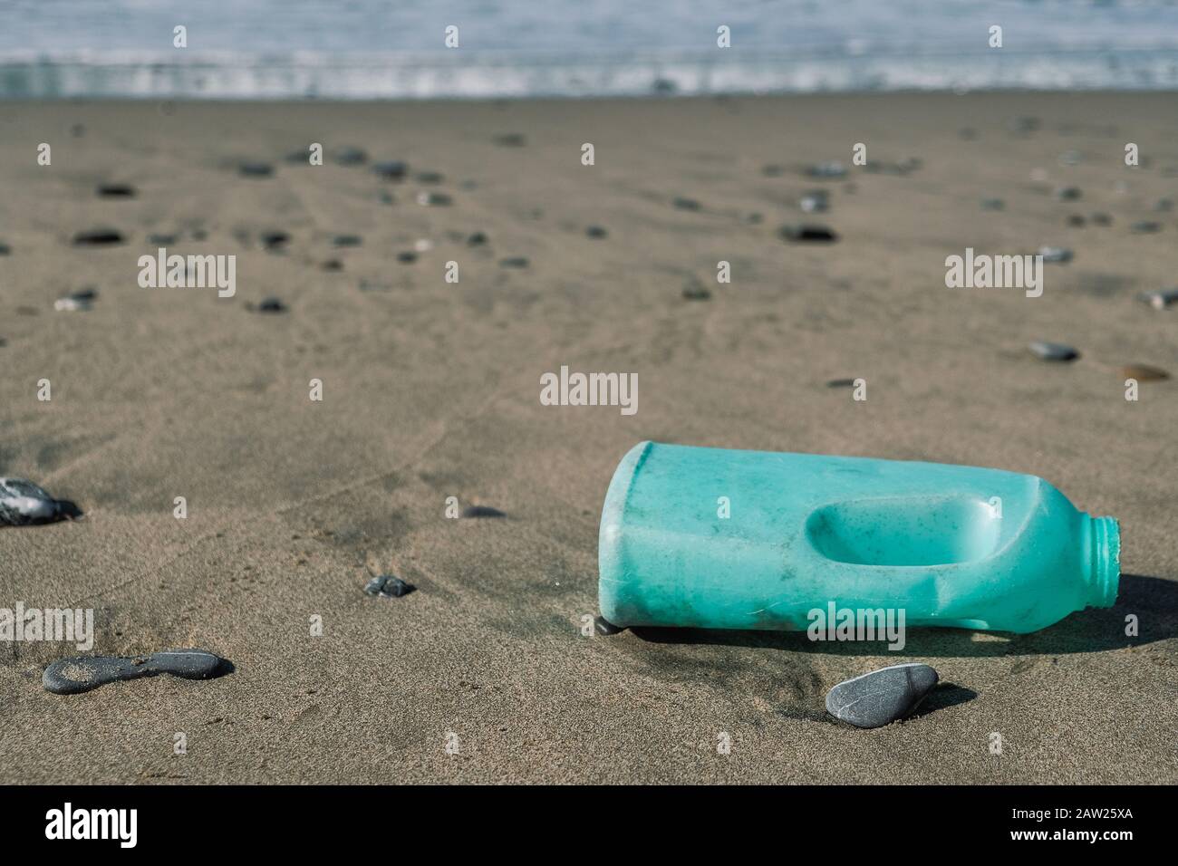 Contenitore di sapone di plastica sulla costa selvaggia del mare ecosistema inquinato, rifiuti industriali Foto Stock