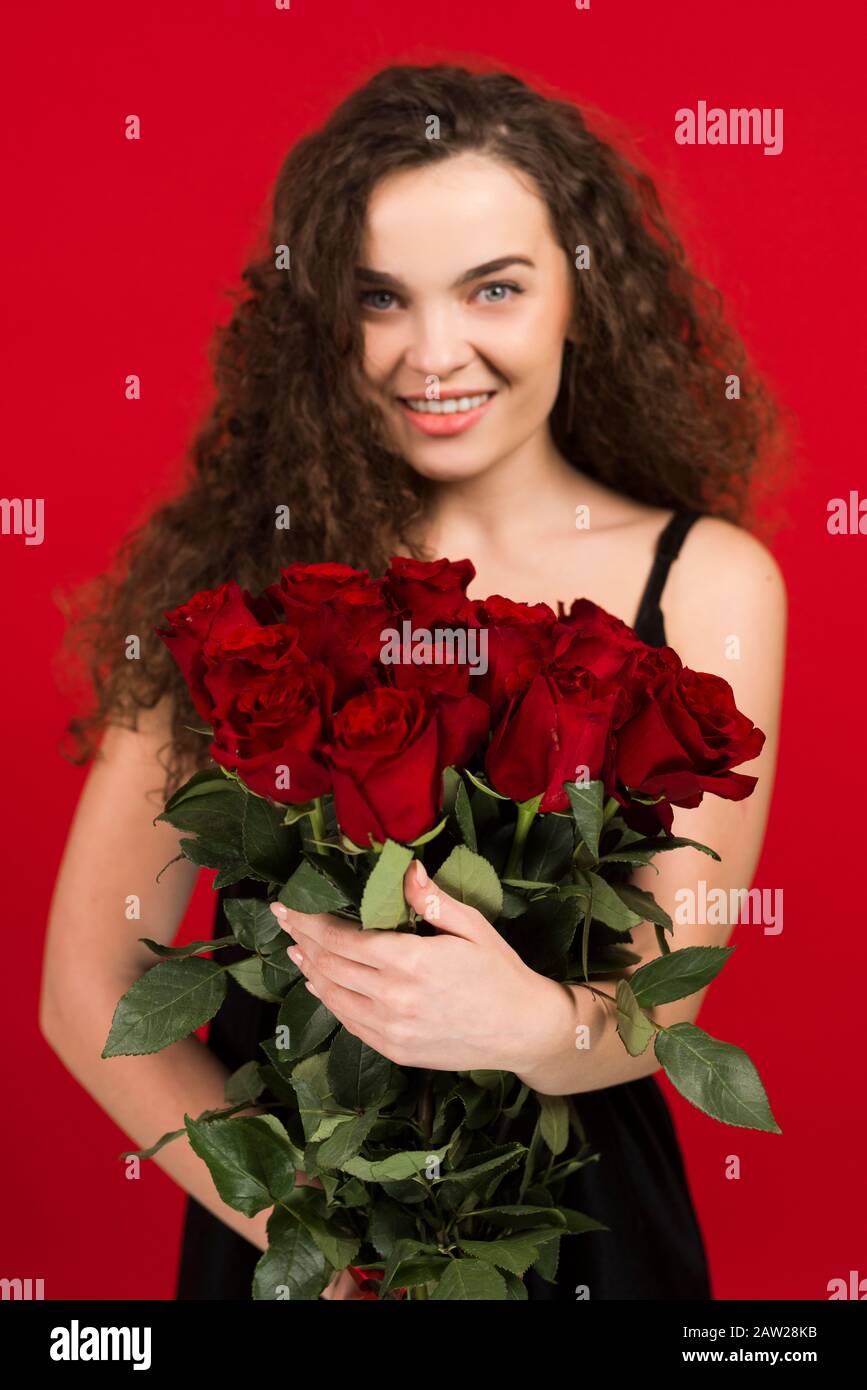 Felice giovane donna che tiene fiori isolati su sfondo rosso. Foto Stock Felice giovane donna che tiene fiori isolati su sfondo rosso. Foto Stock