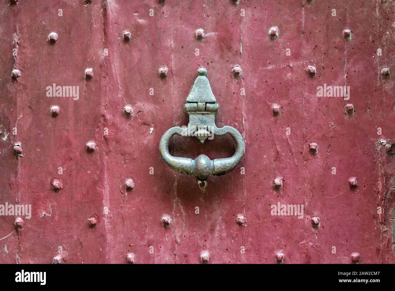 antica maniglia in ottone medievale su una vecchia porta rossa d'ingresso Foto Stock