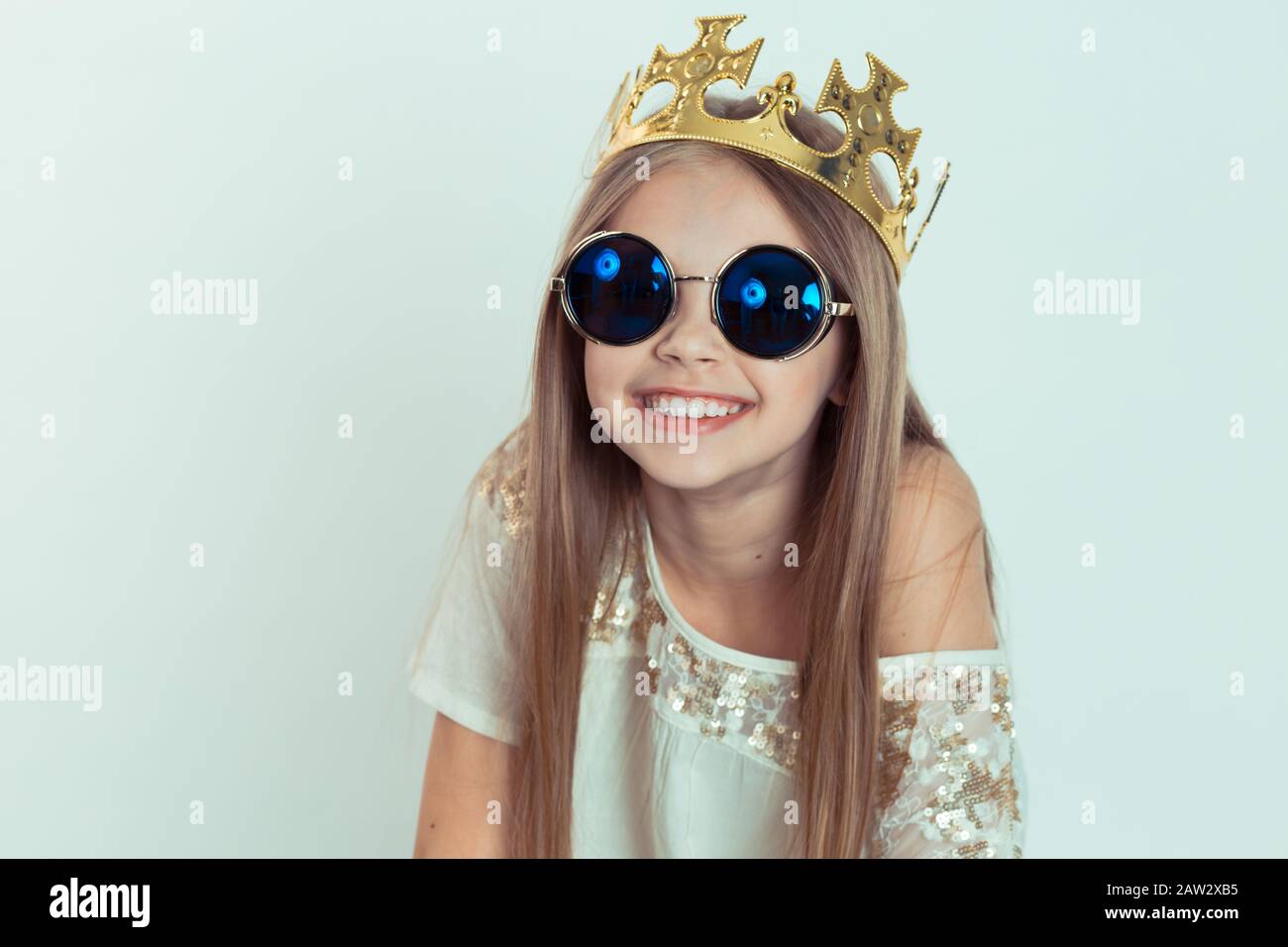 Ragazza giovane con un sorriso carino che indossa una corona, occhiali da  sole a forma rotonda