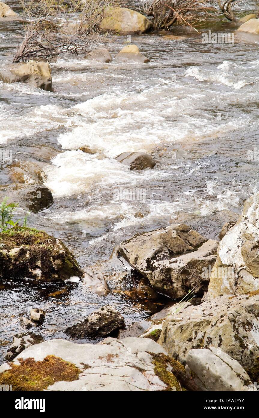 Rocce in un fiume che causa acqua bianca schiumosa. Foto Stock