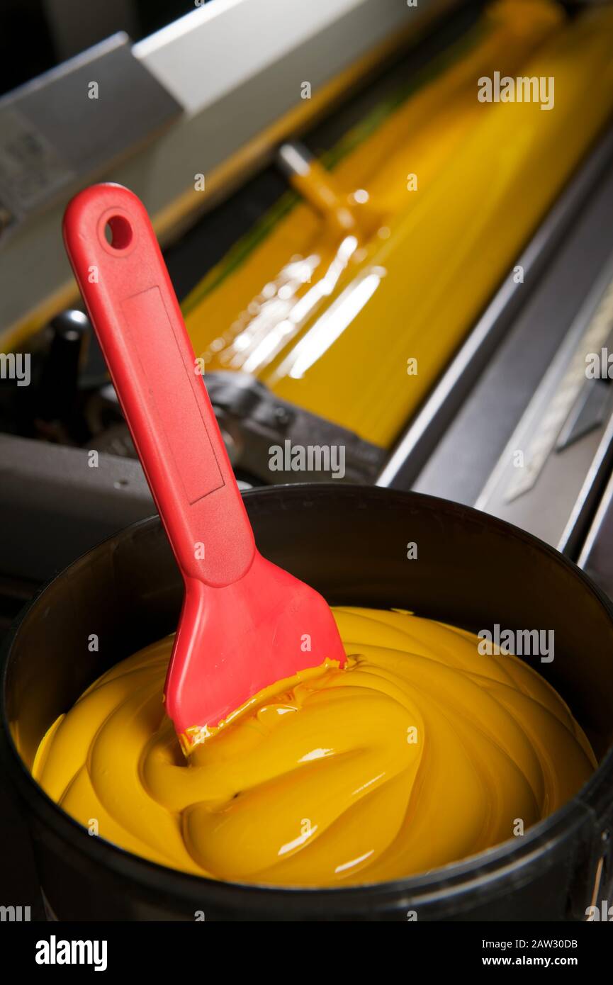 Spatole rosse in barattolo di vernice giallo per l'industria della stampa Foto Stock