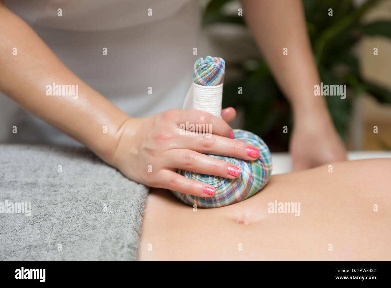 Donna che ha un massaggio addome con borse aromatiche di erbe nel salone cosmetico Foto Stock